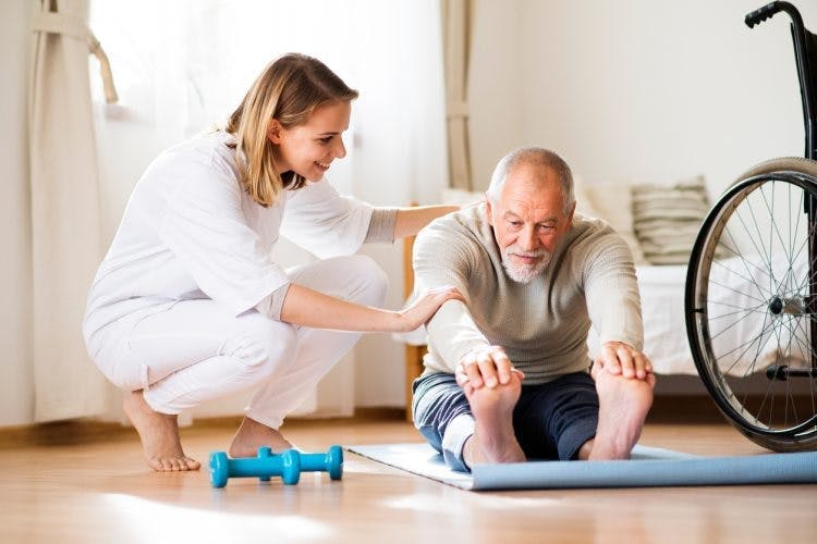 physiotherapist helping stroke patient with forward bend passive exercise