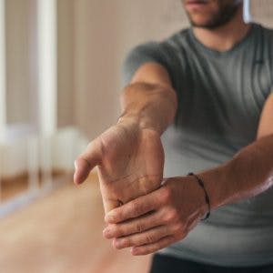 man stretching wrist for passive range of motion exercises for stroke patients at home