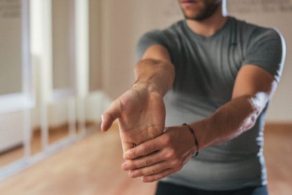 man stretching wrist for passive range of motion exercises for stroke patients at home