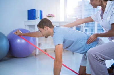 Hombre haciendo terapia física para el tratamiento del derrame cerebral.