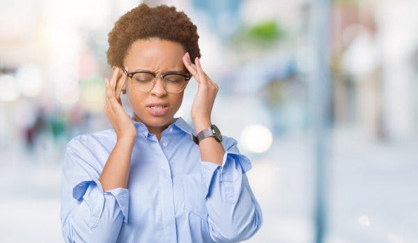 smart woman with glasses experiencing headache and rubbing temples