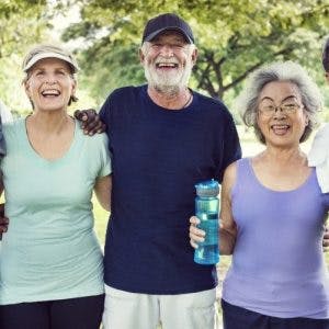 smiling senior friends with arms around each other after exercising with massed practice