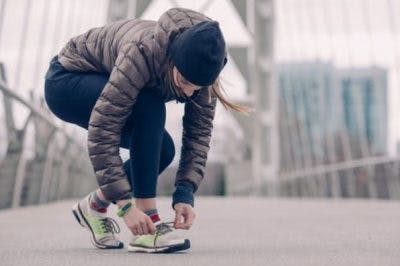 woman tying shoes getting ready to go for a run on a foggy winter morning