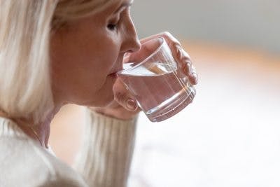 woman drinking glass of water slowly because she has dysphagia after head injury