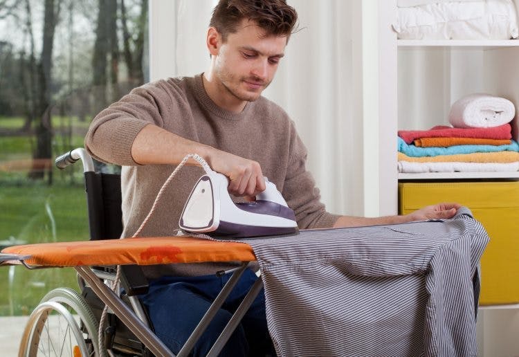 tbi patient in wheelchair ironing a shirt for occupational therapy activities