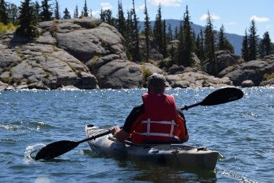 man paddling kayak in mountain lake