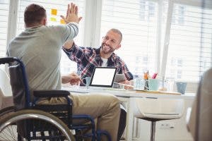 Man giving high-five to person in wheelchair 