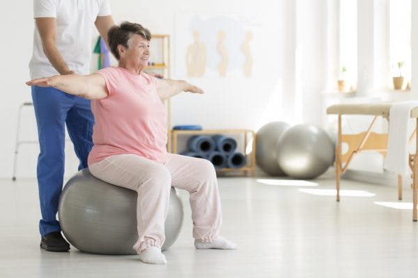 senior exercising on exercise ball because she has balance problems after cerebellum brain damage