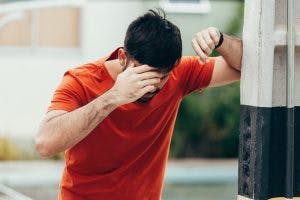 hombre apoyado en la pared porque tiene mareos y pérdida de equilibrio, síntomas de daño cerebral del cerebelo