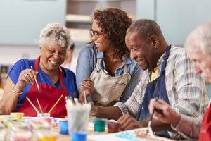 group of seniors laughing and painting during art therapy for brain injury patients