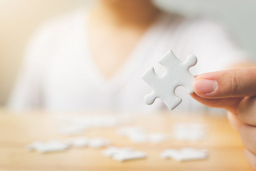 Man holding a puzzle piece, performing a neuropsychological test