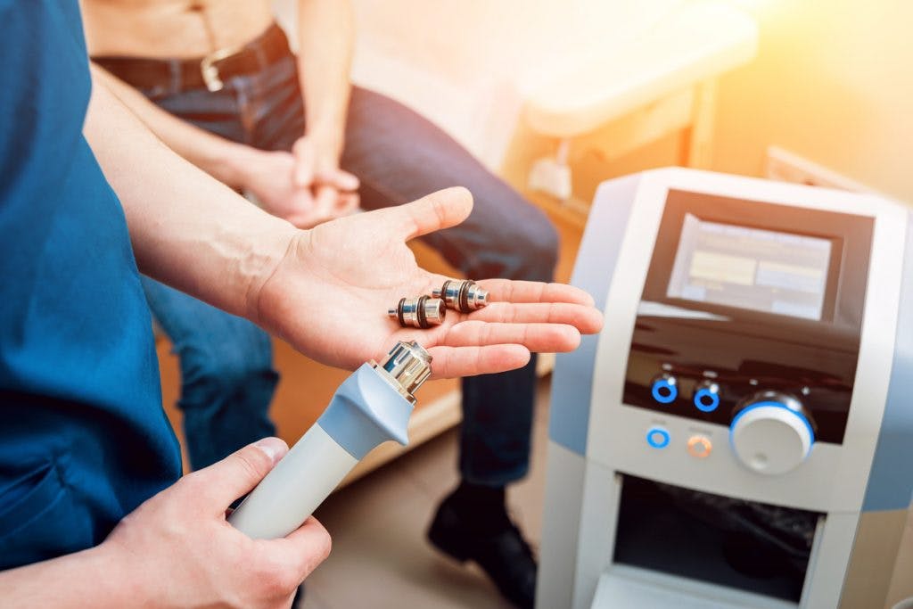 therapist holding cold laser wand showing patient how it works