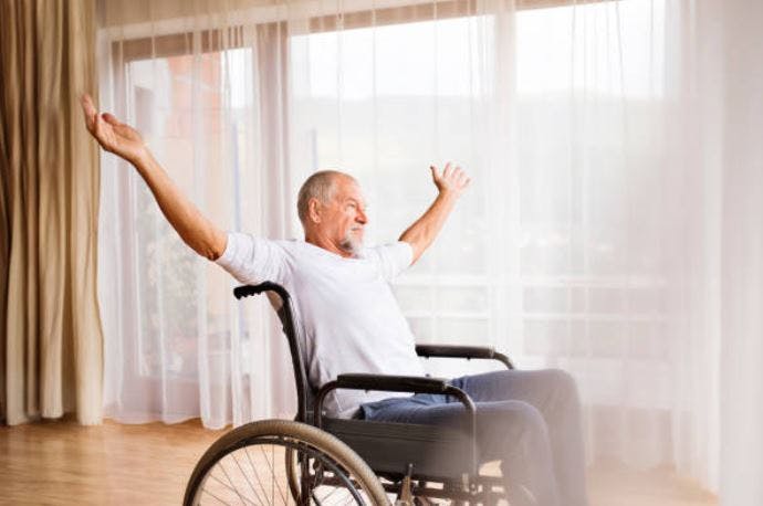 spinal cord injury patient in wheelchair with arms raised overhead to illustrate thoracic level injury and readiness to achieve balance exercises