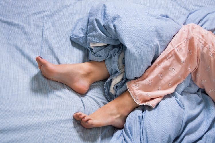 woman with restless leg syndrome fidgeting in bed