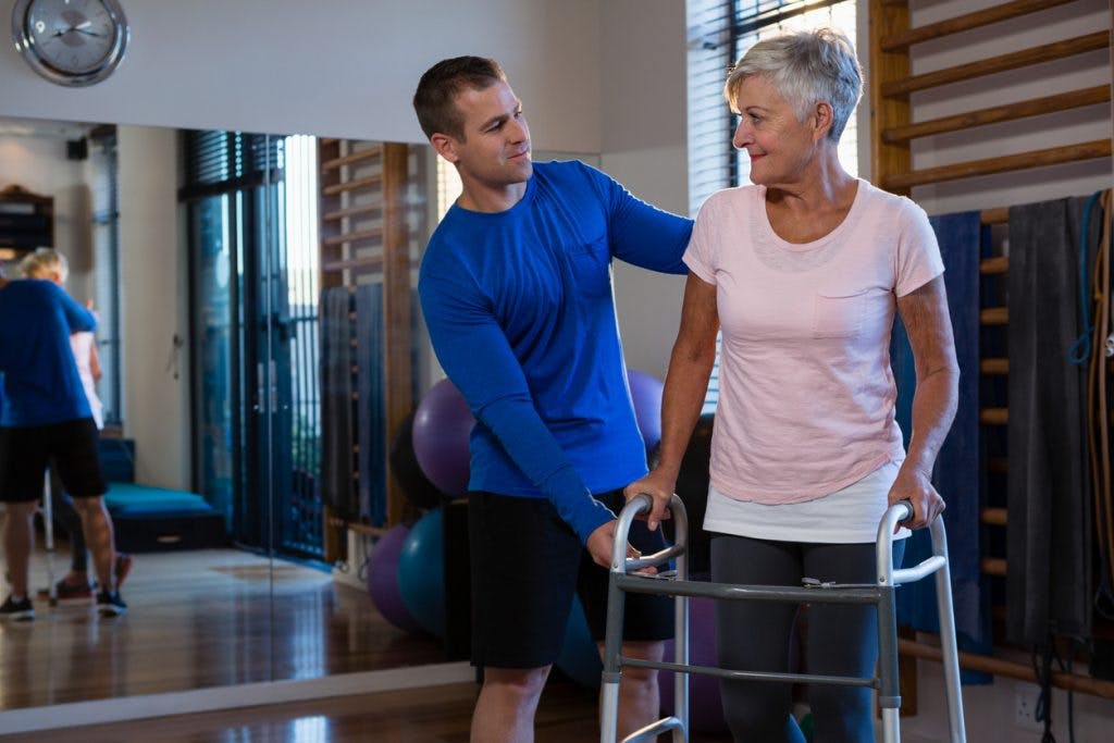 Woman using walker during gait training session with therapist