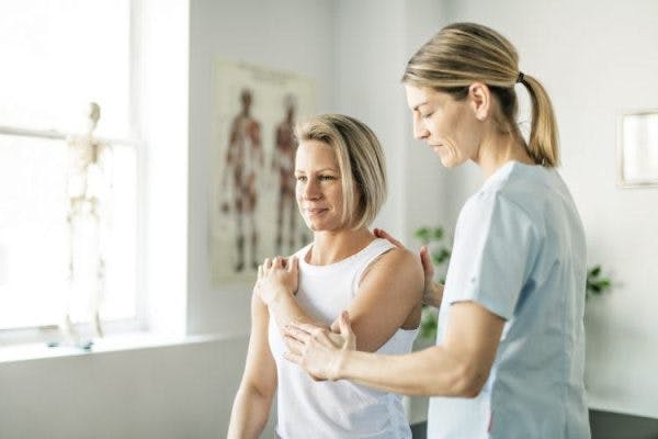 therapist assisting patient in spinal cord injury shoulder exercises