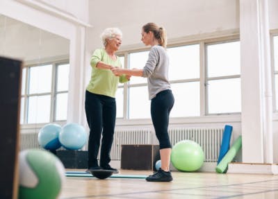 Woman standing on balance board during vestibular training, another physical therapy intervention for TBI