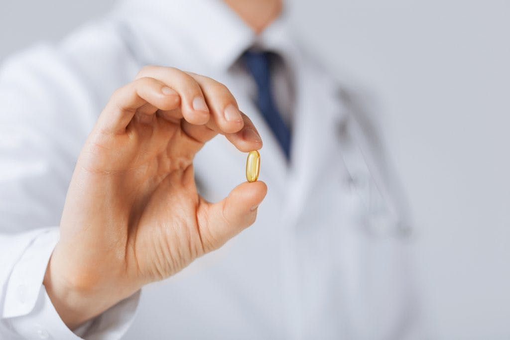 doctor hand showing one capsule of fish oil for brain injury