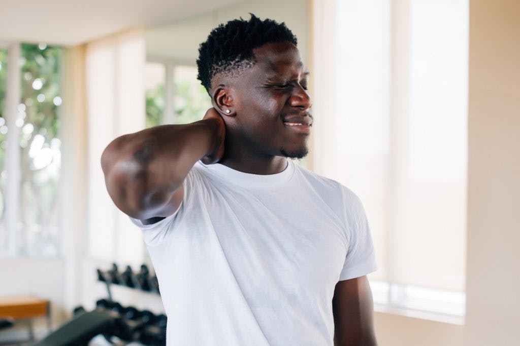 man rubbing neck suffering from symptoms of post-traumatic cervical dystonia