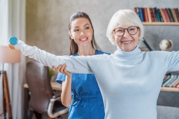 Senior woman training with physiotherapist at home to overcome primary motor cortex damage