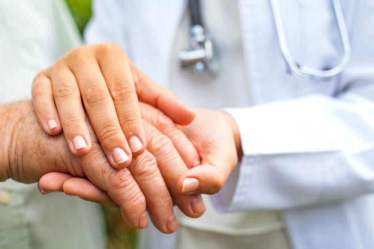 Close up of doctor holding elderly man's trembling hand