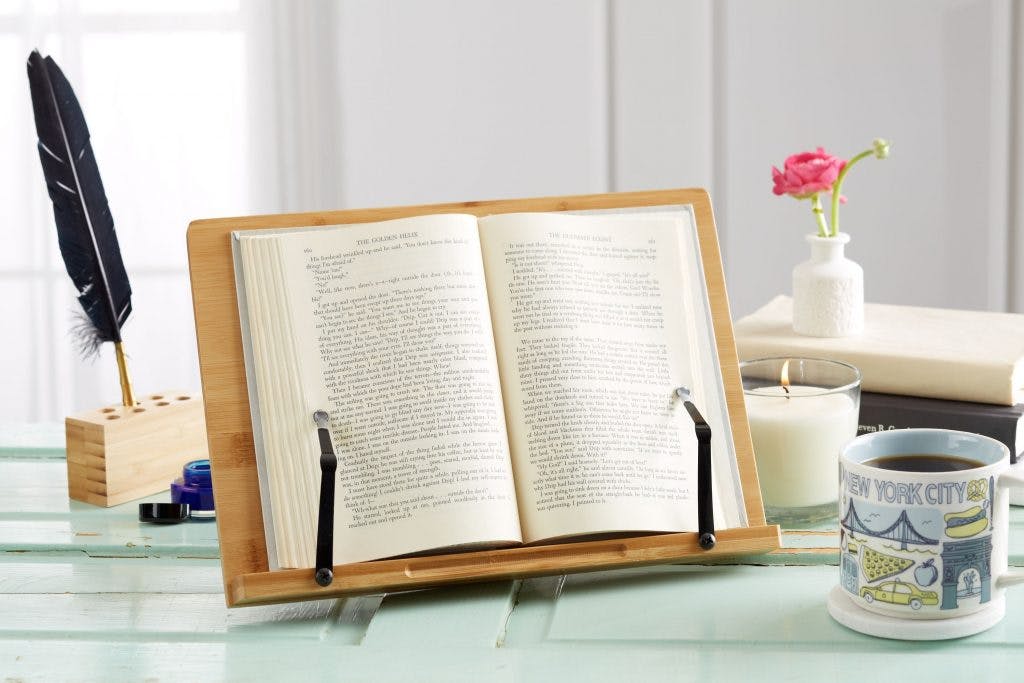 book holder on desk with coffee mug and quill pen 