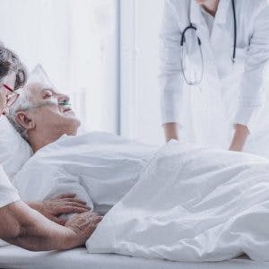 stroke patient lying in hospital bed surrounded by family members