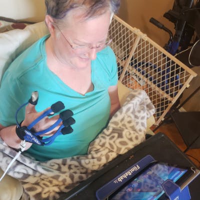 survivor smiling while playing MusicGlove from her tablet