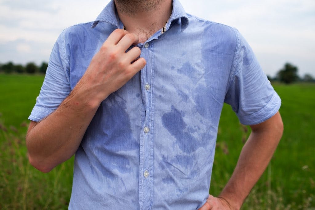 Man sweating through shirt because he has hyperhidrosis