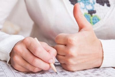 close-up of man giving a thumb's up while doing a word search puzzle, an excellent exercise for left neglect after brain injury