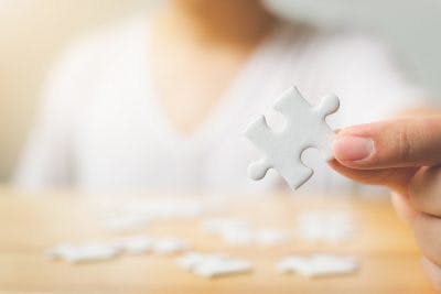 close up of hand holding white puzzle piece