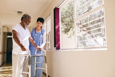 therapist helping stroke patient with a walker to improve chances of a full recovery from stroke