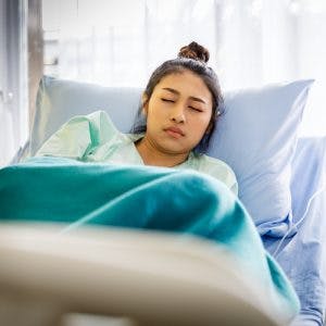 一名脑部受伤的女子躺在医院病床上挣扎着呕吐