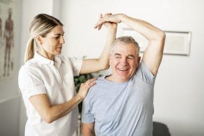 physical therapist working with spinal cord injury survivor to increase movement and mobility