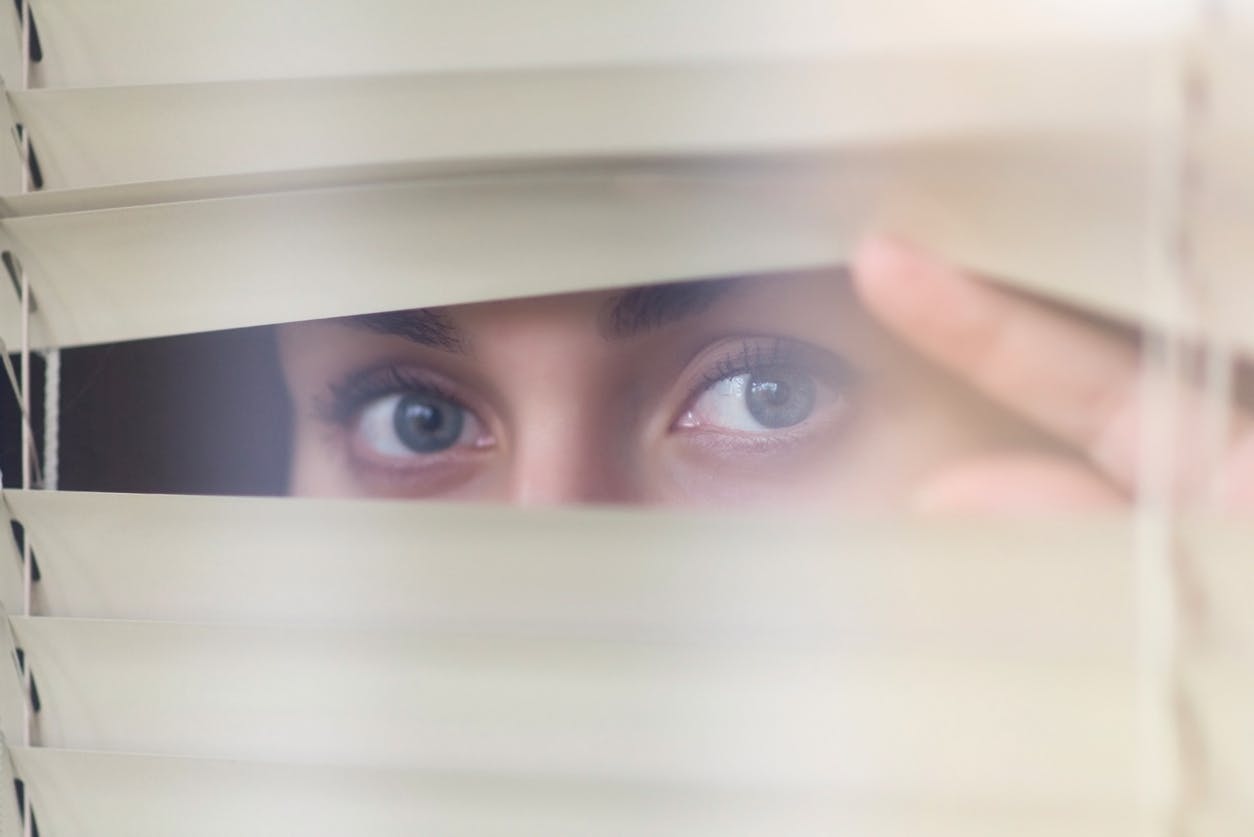 woman's eyes peeking through blinds