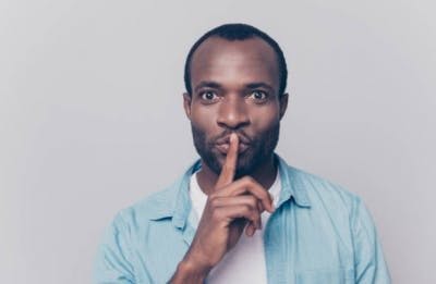 man putting finger over mouth to be quiet