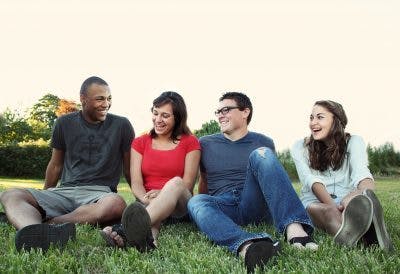 four friends sitting on grass and laughing
