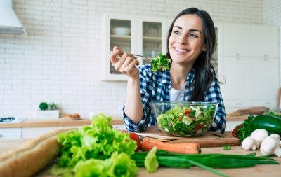 woman smiling and eating salad