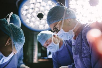 Concentrated surgeon performing craniotomy with her team