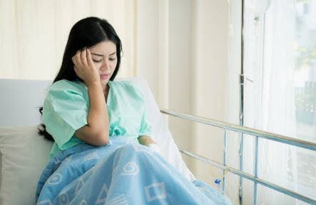 Frau, die mit Kopfschmerzen im Krankenhausbett kämpft