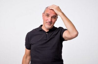 middle aged man rubbing forehead looking confused