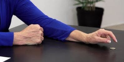 therapist placing a quarter down on the table for hand therapy