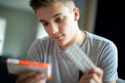 teenage boy reading label of Adderall for TBI