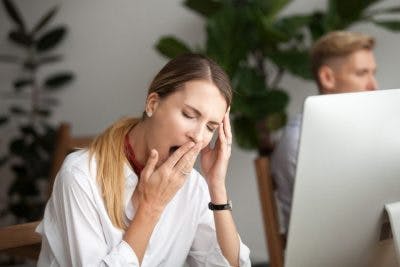 woman sitting at computer and yawning