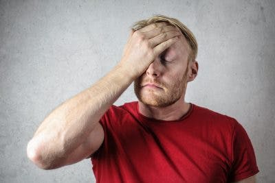 frustrated, tense man rubbing his face because he has high blood pressure after head injury