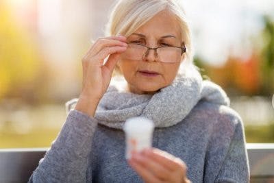 senior woman reading label of bottle of Ritalin for brain injury