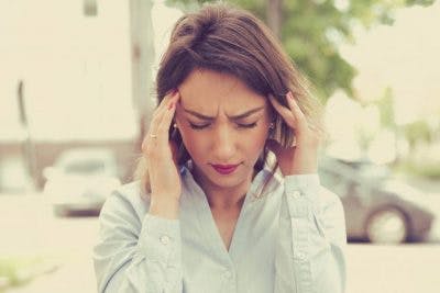 woman rubbing her temples because she has light sensitivity after head injury