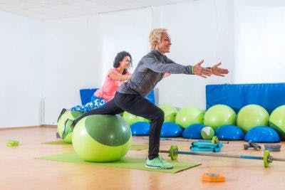 woman practicing vestibular therapy with exercise instructor to help her overcome light sensitivity after head injury