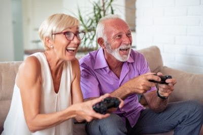 Happy senior couple playing video game for TBI recovery