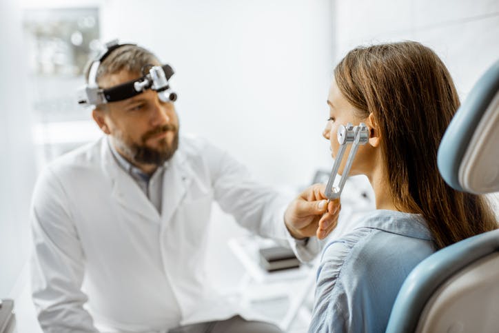 doctor performing hearing test with tuning forks on brain injury patient